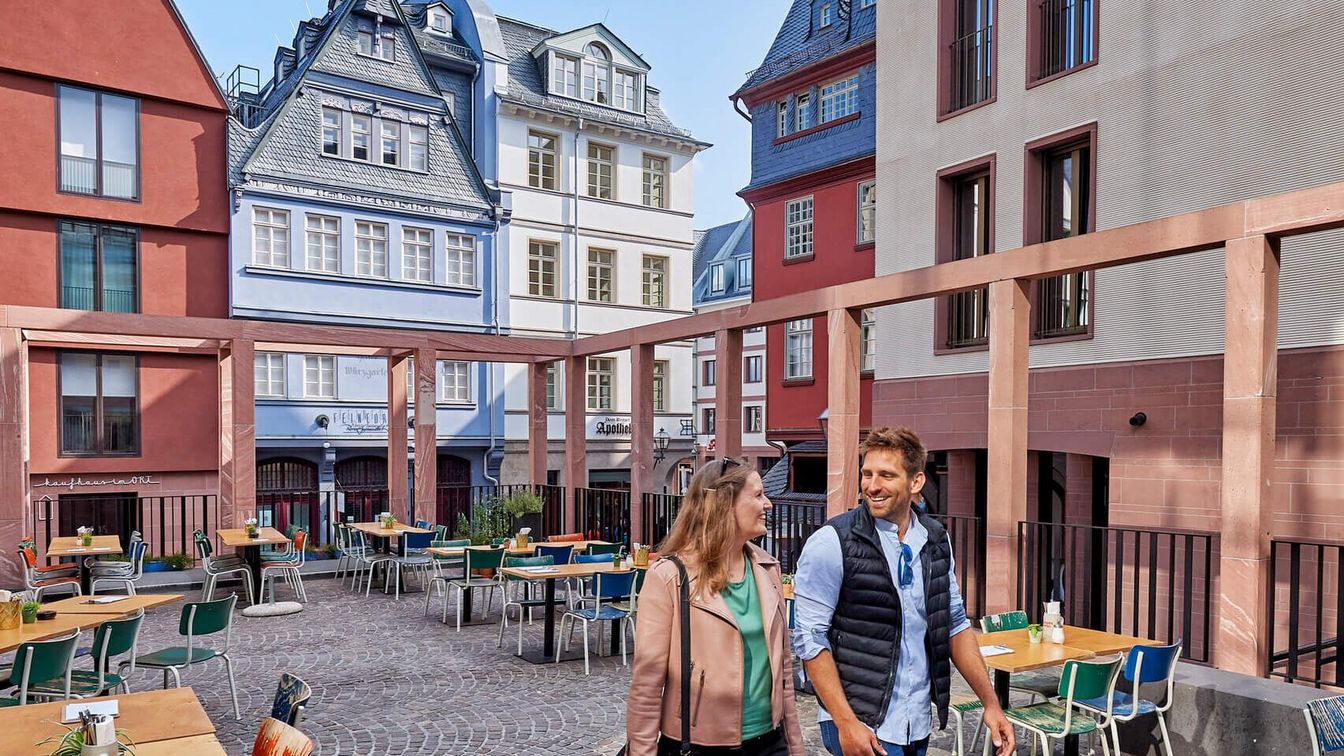 Ein Paar spaziert durch die Neue Altstadt, alte rekonstruierte Häuser im Hintergrund