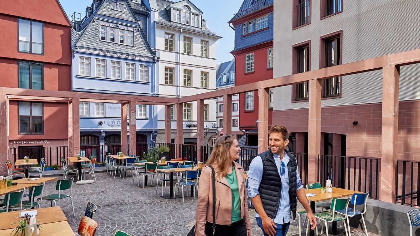 A couple walks through the New Old Town, old reconstructed houses in the background