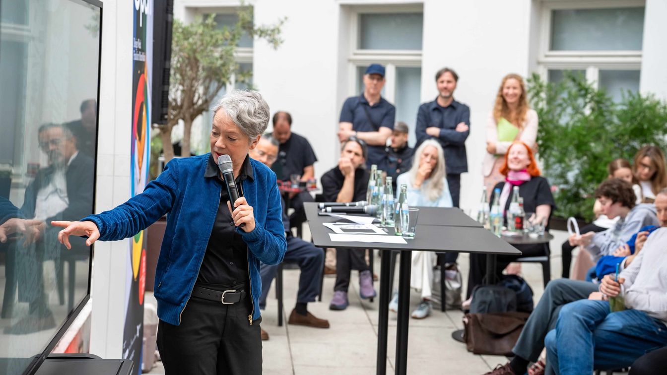 Rednerin mit Mikrofon spricht bei einer Open-Air-Veranstaltung vor Publikum in Frankfurt.