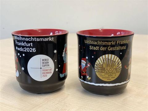 Zwei Glühweintassen, außen schwarz, innen rot mit Motiven zum Thema Gestaltung.