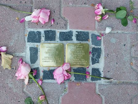 Zwei Stolpersteine für Georg und Susanne Silberstein, von Blumen umgeben, eingebettet im Gehweg. 