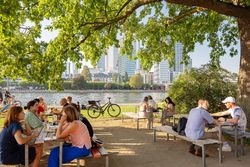 In summer, some guests sit on wooden benches in the Maincafé on the banks of the Main.